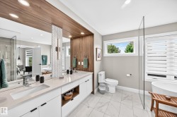 Contemporary bathroom featuring a double vanity with integrated sinks, quartz countertops, and white cabinetry with matte black hardware - 