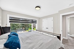 Bedroom featuring a large window with privacy blinds, dual white panel doors, wall-to-wall carpeting, and a flush-mount ceiling light - 
