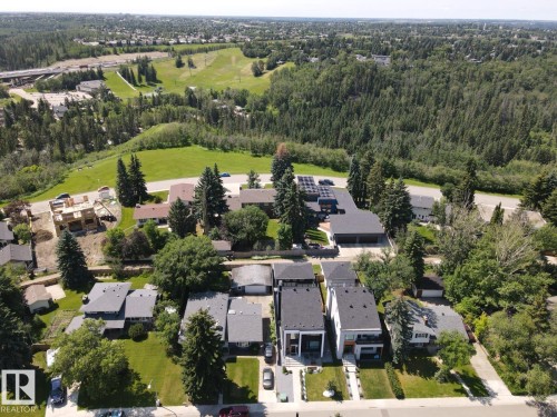 Aerial perspective showcasing a residential area with varied architectural styles, surrounded by abundant mature trees and expansive green spaces - 12631 52 Avenue, Edmonton, AB 