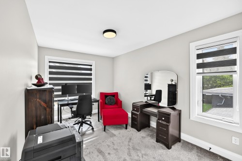 Light-filled room featuring neutral wall tones, plush gray carpeting, two windows with horizontal blinds, and a ceiling-mounted light fixture - 12631 52 Avenue, Edmonton, AB 