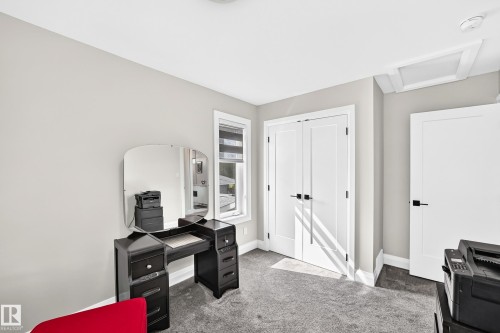 Carpeted room featuring a double-door closet with matte black hardware, a single entry door, and a window with blinds - 12631 52 Avenue, Edmonton, AB 