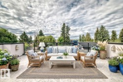 Expansive rooftop patio featuring neutral-toned tile flooring, clear glass railings, and a white perimeter wall - 