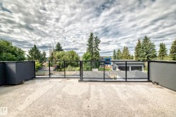 Expansive rooftop deck featuring a concrete surface, modern glass railing, and black metal planters - 