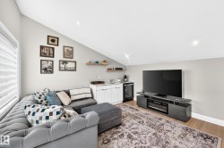 Vaulted ceiling living area featuring wood-finish flooring, a built-in wet bar with white cabinetry, under-counter beverage refrigerator, and recessed lighting - 