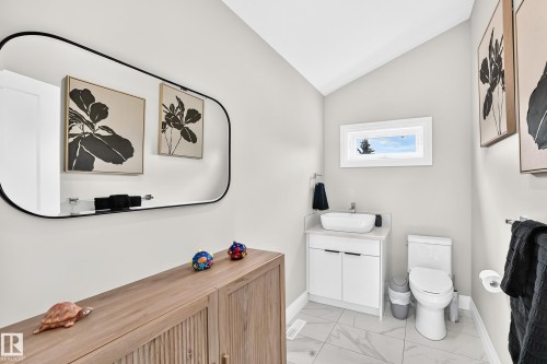 Powder room featuring a vaulted ceiling, rectangular window, and wood-finish cabinetry - 12631 52 Avenue, Edmonton, AB 