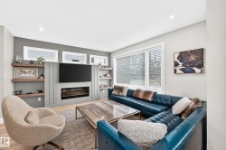 Living area featuring a built-in media wall with integrated fireplace, wood-finish flooring, and recessed lighting - 