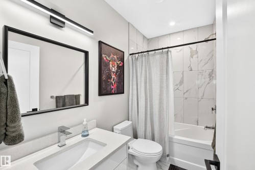 Contemporary bathroom featuring a vanity with an integrated rectangular sink, chrome single-handle faucet, and black framed mirror - 12631 52 Avenue, Edmonton, AB 
