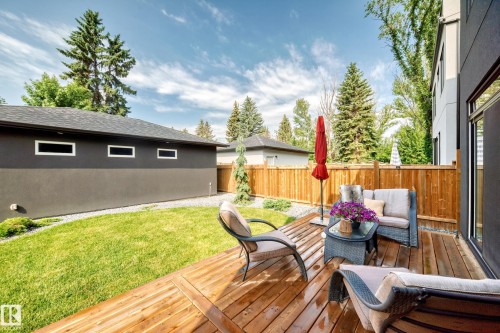 Expansive wood deck with a privacy fence, overlooking a manicured lawn and mature trees - 12631 52 Avenue, Edmonton, AB 