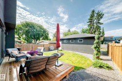 Expansive outdoor living area featuring a wood-plank deck, lush green lawn, and a gravel pathway - 