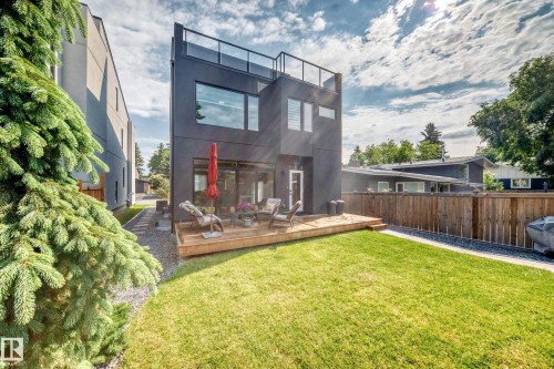 Modern multi-story exterior featuring a rooftop deck with glass railing, large format windows, and a ground-level wood deck - 12631 52 Avenue, Edmonton, AB 
