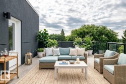 Expansive rooftop patio featuring a dark exterior wall, glass panel railings, and a concrete surface - 