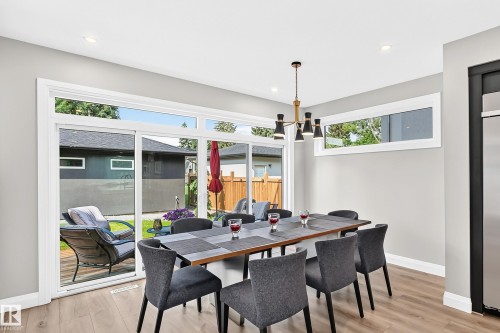 Dining area featuring wood-finish flooring, a contemporary chandelier, recessed lighting, and expansive sliding glass doors - 12631 52 Avenue, Edmonton, AB 