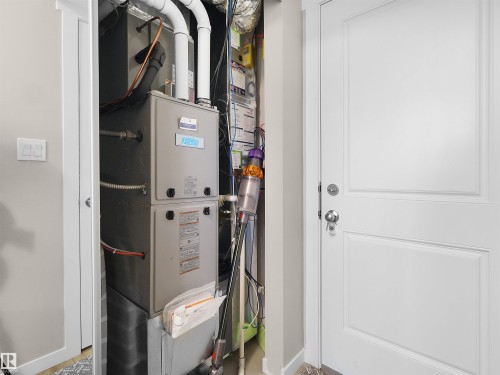 Utility closet featuring a central HVAC system with visible ductwork and piping, and a white paneled door - 49 17832 78 Street, Edmonton, AB 