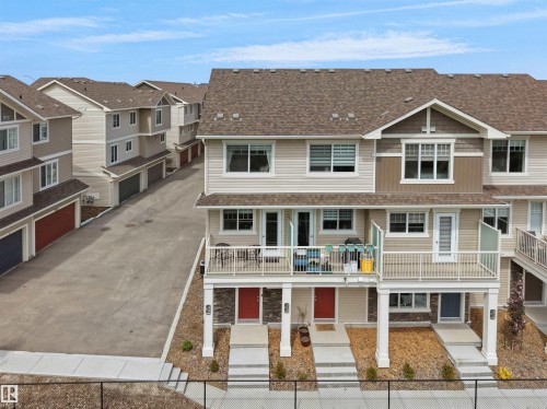 Multi-level townhome exterior featuring light-toned siding and a prominent upper-level balcony with white railings - 49 17832 78 Street, Edmonton, AB 