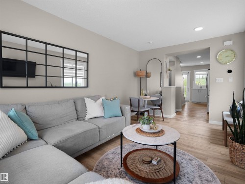 Open-concept living area with light wood-finish flooring, recessed lighting, and a neutral wall palette - 49 17832 78 Street, Edmonton, AB 