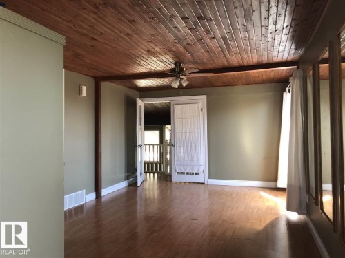 Room featuring wood-finish flooring, a plank wood ceiling, and a ceiling fan with integrated lighting - 11507 141 Avenue, Edmonton, AB 