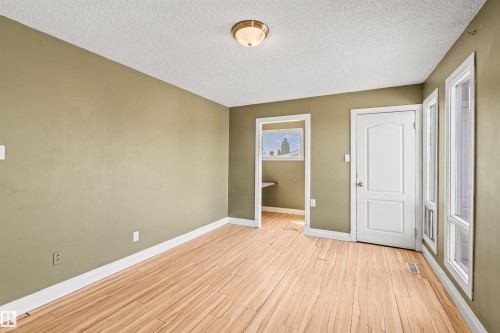 Expansive room featuring wood-finish flooring, light olive-toned walls, and bright white trim - 11507 141 Avenue Nw, Edmonton, AB - Indoor Photo Showing Other Room