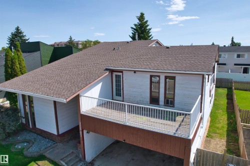 Exterior featuring a spacious elevated deck with white railings, a brown shingle roof, and a gravel-edged garden area - 11507 141 Avenue Nw, Edmonton, AB - Outdoor With Deck Patio Veranda With Exterior
