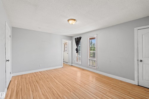 Spacious room featuring light wood-finish flooring, light gray walls, white trim, and a ceiling-mounted light fixture - 11507 141 Avenue Nw, Edmonton, AB - Indoor Photo Showing Other Room