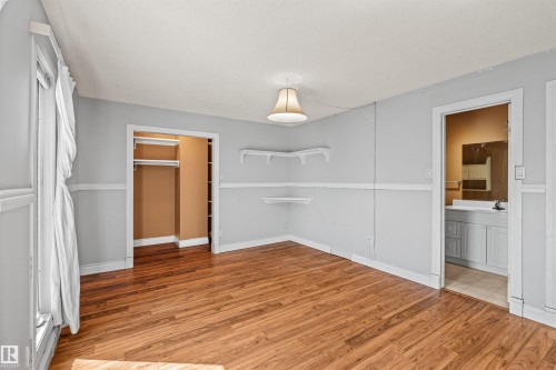 Spacious room featuring wood-finish flooring, light gray walls with chair rail molding, and a ceiling-mounted light fixture - 11507 141 Avenue Nw, Edmonton, AB - Indoor Photo Showing Other Room