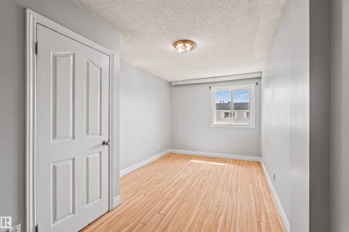 Room featuring wood-finish flooring, light grey walls, and a white paneled door - 11507 141 Avenue Nw, Edmonton, AB - Indoor Photo Showing Other Room
