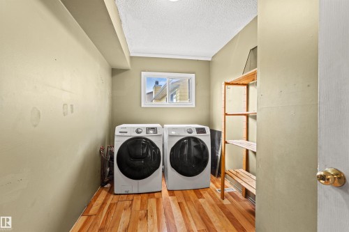 Dedicated laundry area featuring wood-finish flooring and a white-framed window - 11507 141 Avenue Nw, Edmonton, AB - Indoor Photo Showing Laundry Room