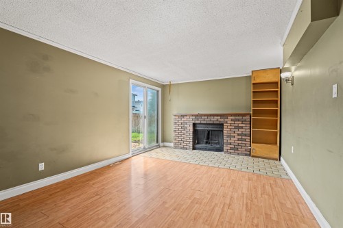 Living area with wood-finish flooring and a brick fireplace - 11507 141 Avenue Nw, Edmonton, AB - Indoor With Fireplace