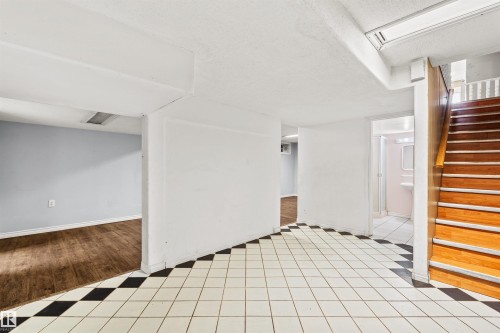 Entry area featuring black and white checkerboard tile flooring, a wood staircase, and multiple doorways - 11507 141 Avenue Nw, Edmonton, AB - Indoor Photo Showing Other Room