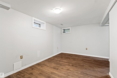 Spacious room featuring wood-finish flooring, light gray walls, and white trim - 11507 141 Avenue Nw, Edmonton, AB - Indoor Photo Showing Other Room