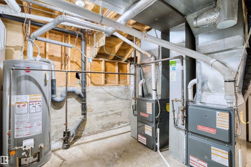 Utility area featuring a water heater, two Goodman furnaces, and exposed ductwork - 11507 141 Avenue Nw, Edmonton, AB - Indoor Photo Showing Basement