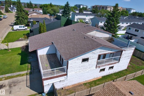 Property featuring a multi-level design with a shingle roof and a flat roof section, an exterior deck with white railings, and a secondary exterior balcony with white railings - 11507 141 Avenue Nw, Edmonton, AB - Outdoor