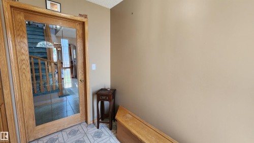 Entryway featuring a wood-framed door with glass panels, patterned tile flooring, and a neutral wall color - 2708 44A Avenue, Edmonton, AB 