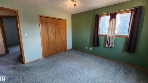 Broadloom carpeting throughout, complemented by a window with natural light, wood-finish trim, and a bi-fold closet with wood-finish doors - 2708 44A Avenue, Edmonton, AB 