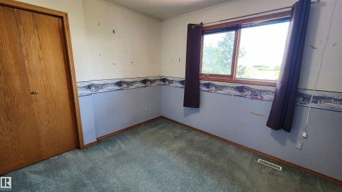 Room featuring a wood-framed window, light blue wall paneling, and a wood-finish interior door - 2708 44A Avenue, Edmonton, AB 