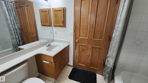 Bathroom featuring a single vanity with an integrated sink, light-toned countertop, and wood-finish cabinetry - 2708 44A Avenue, Edmonton, AB 