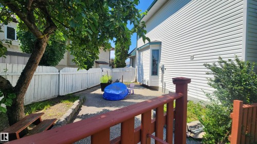 Private side yard featuring a paved patio area, white picket fence, and mature tree providing shade - 2708 44A Avenue, Edmonton, AB 