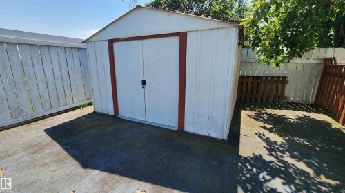 Detached storage shed with a peaked roof, white siding, and red trim - 2708 44A Avenue, Edmonton, AB 