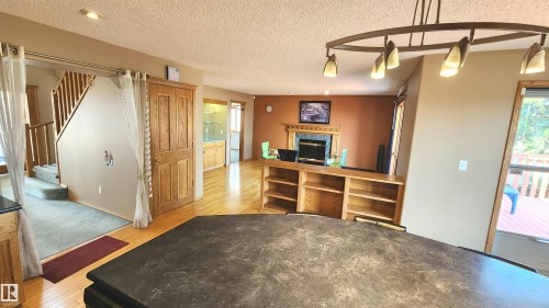 Open-concept living area featuring a built-in fireplace with a decorative mantel, hardwood flooring, and a multi-tiered staircase with wooden railings - 2708 44A Avenue, Edmonton, AB 