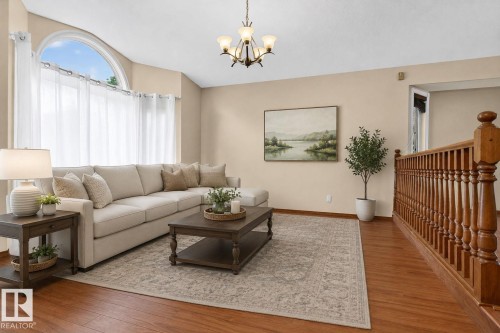 Living area featuring wood-finish flooring, an arched window, and a chandelier - 5612 Mcleod Road, Edmonton, AB 