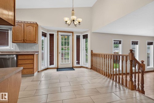 Kitchen area featuring wood cabinetry, stainless steel dishwasher, and tiled backsplash - 5612 Mcleod Road, Edmonton, AB 