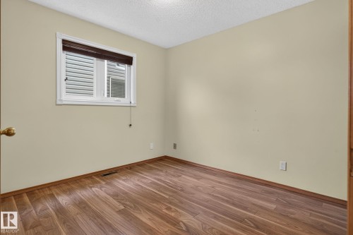 Room featuring wood-finish flooring, light beige wall paint, white trim, and a window with blinds - 5612 Mcleod Road, Edmonton, AB 
