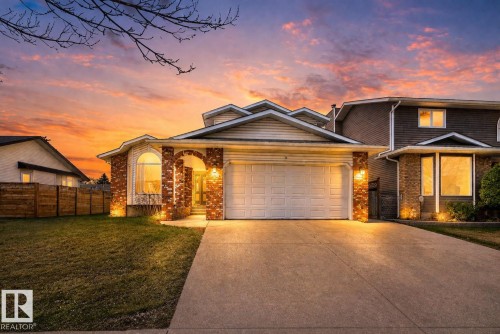 Front exterior featuring a concrete driveway, attached garage, brick facade accents, and a curved bay window - 5612 Mcleod Road, Edmonton, AB 