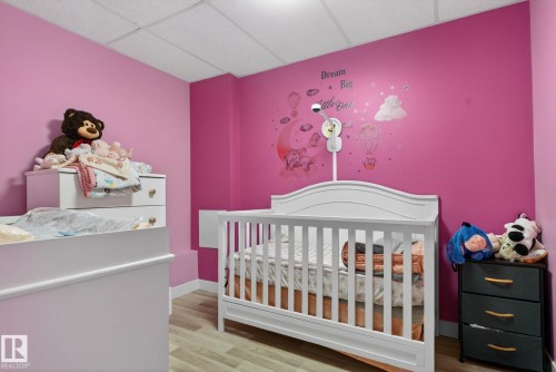 Room featuring vibrant pink walls, light wood-finish flooring, and a drop ceiling - 5612 Mcleod Road, Edmonton, AB 