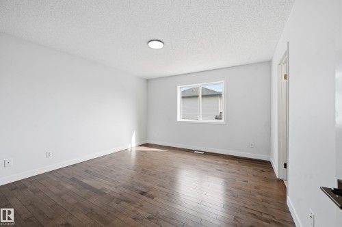 Spacious room featuring wood-finish flooring, a single window, white walls, and a ceiling-mounted light fixture - 631 Jenner Cove Cove, Edmonton, AB 