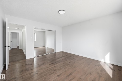 Spacious room featuring wood-finish flooring, white walls, and a ceiling-mounted light fixture - 631 Jenner Cove Cove, Edmonton, AB 