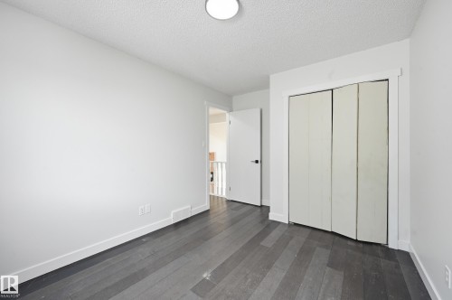 Bedroom featuring grey wood-finish flooring, white walls, and a bi-fold closet - 631 Jenner Cove Cove, Edmonton, AB 