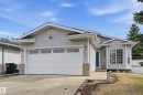 Siding exterior home featuring an attached two-car garage, bay window, concrete front walkway, stone facade accents, and a blue front door - 631 Jenner Cove Cove, Edmonton, AB 