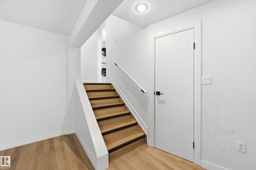 Staircase featuring wood-finish treads and risers, a white half-wall railing, and a black handrail - 631 Jenner Cove Cove, Edmonton, AB 