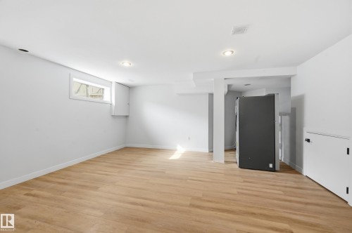 Spacious room featuring light wood-finish flooring, recessed lighting, a horizontal window, and white painted walls - 631 Jenner Cove Cove, Edmonton, AB 