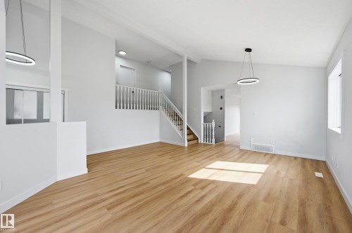 Spacious interior featuring wood-finish flooring, white walls, and contemporary pendant lighting - 631 Jenner Cove Cove, Edmonton, AB 